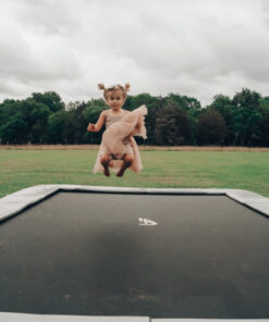 toddler jumping on gray inground trampoline