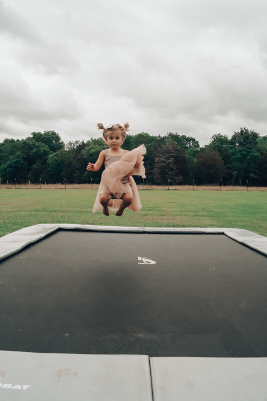 10ft x 6ft Akrobat Primus Flat In-Ground Trampoline - Anthracite Gray Pad with Black Jump Mat 2 toddler jumping on gray inground trampoline