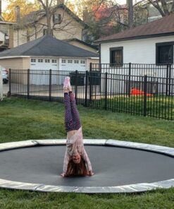 child doing a trick on a gray round inground trampoline