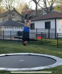 child doing a trick on a gray round inground trampoline