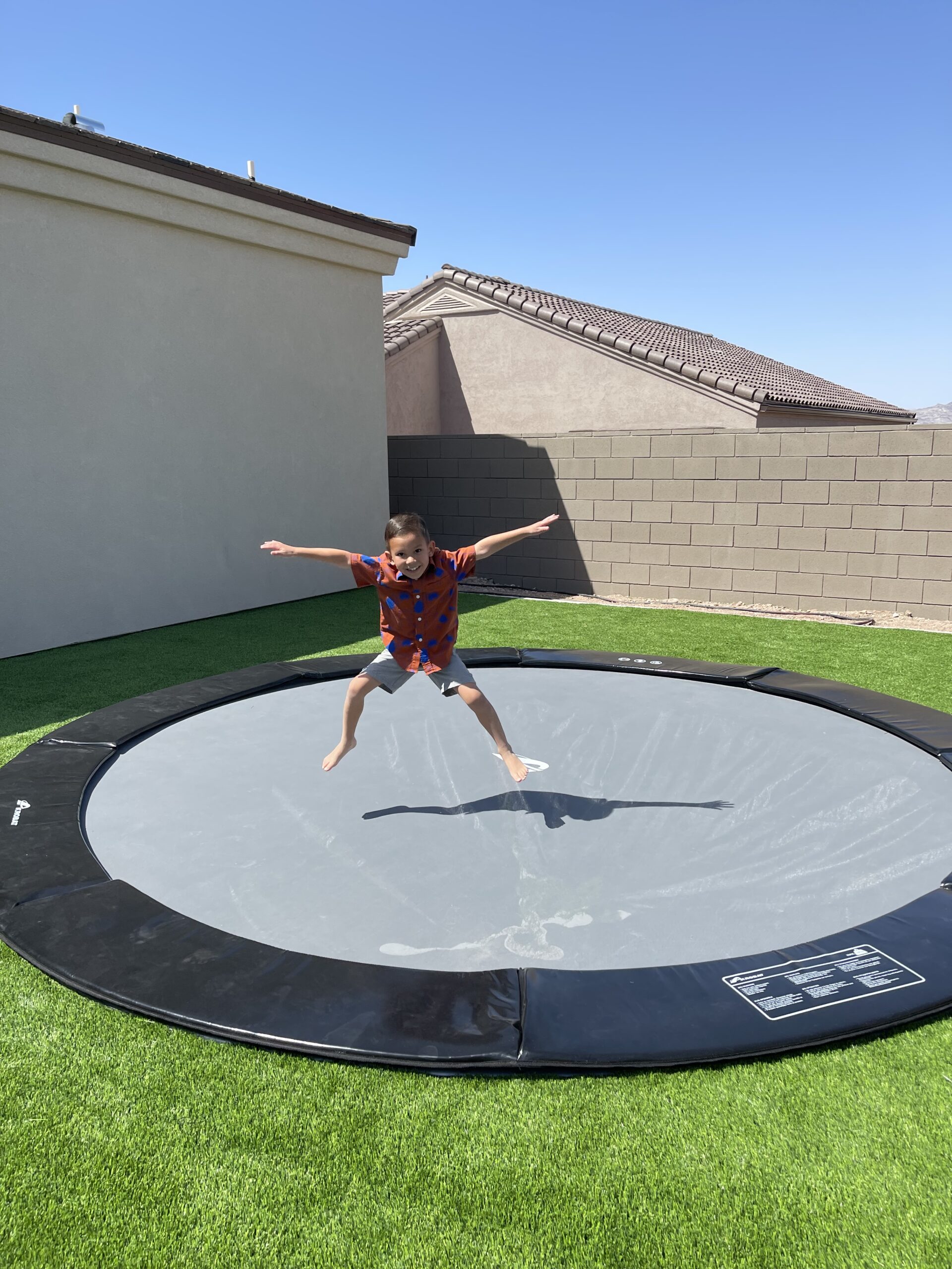 10ft Round Akrobat Primus Flat In-Ground Trampoline - Black Pad with Gray Jump Mat 3 child jumping on a black round inground trampoline