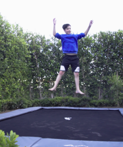 child jumping on a rectangular gray inground trampoline