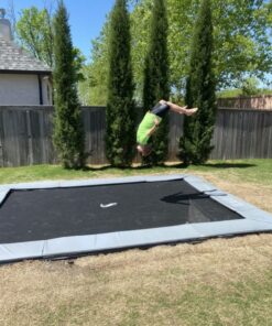 child doing a trick on a gray rectangular inground trampoline