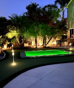 A tranquil nighttime backyard scene showcasing a glowing pool, with ambient lighting enhancing the peaceful atmosphere.