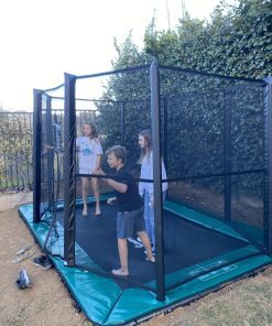 In a vibrant backyard, two children are happily playing on a trampoline, enjoying a sunny day filled with laughter.