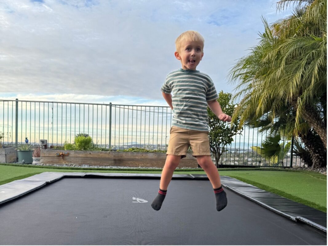 Health Benefits of Trampolines 53 A-young-boy-joyfully-jumps-on-a-trampoline-in-a-sunny-backyard-showcasing-his-excitement-and-energy.